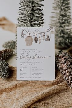 a baby shower is shown with pine cones and fir trees in the background, as well as a card that says merry little baby shower