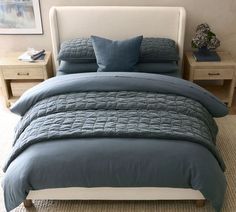 a bed with blue comforter and pillows in a bedroom next to two nightstands