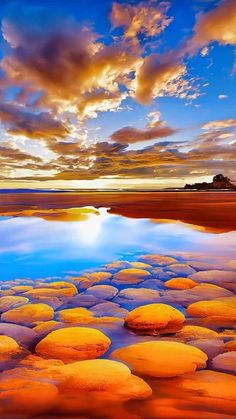 the sun is setting over a body of water with large rocks in front of it