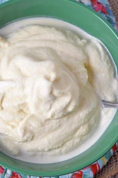 a green bowl filled with whipped cream on top of a blue and white table cloth