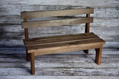 a small wooden bench sitting on top of a wooden floor next to a white wall