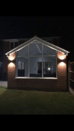 a house that is lit up at night with some lights on the side of it