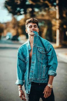 a young man is standing in the street with his mouth open and wearing a jean jacket