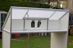 a white chicken coop with two doors and windows