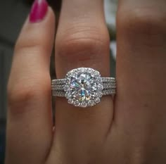 a woman's hand with a diamond ring on top of her finger and the other hand holding an engagement ring