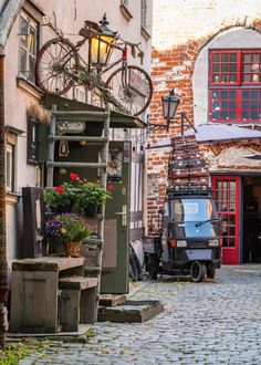 an old truck parked in front of a building with flowers and bicycles on the roof