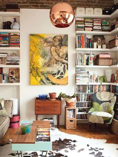 a living room filled with furniture and bookshelves next to a wall mounted painting