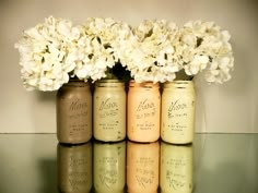 four jars with flowers in them sitting on a table