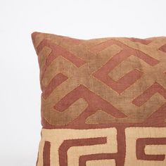 a brown and tan pillow with an intricate design on the front, sitting on a white surface