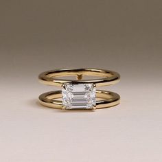 two gold rings with an emerald cut diamond