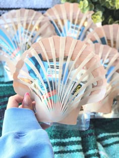 a person holding up a plastic fan in their hand