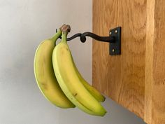 two bananas hanging from a hook on a wall