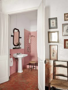 the bathroom is decorated in pink and white with pictures on the wall above the sink