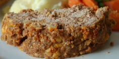 a close up of food on a plate with carrots and mashed potatoes in the background