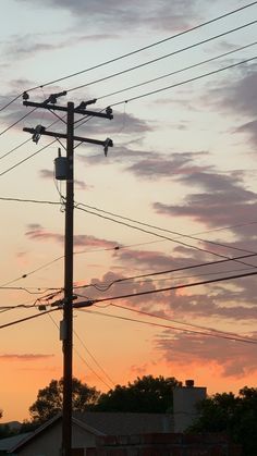 the sun is setting behind some power lines and telephone poles with birds perched on them