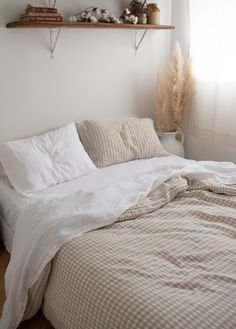 an unmade bed in a bedroom with shelves above it and pillows on the bed