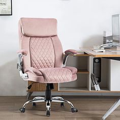 a pink office chair sitting on top of a wooden desk next to a computer monitor