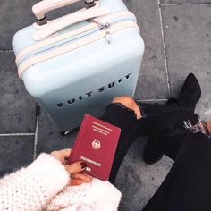 a person sitting on the ground with a passport and suitcase in front of them,