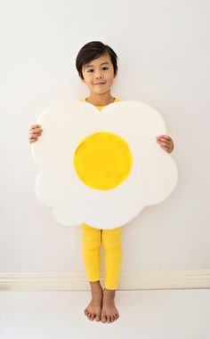 a little boy holding up a fried egg shaped like a pancake