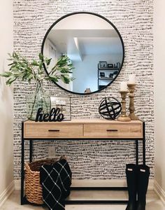 a black and white wall with a round mirror on top of it next to a wooden table