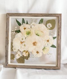 a white flower arrangement in a wooden frame