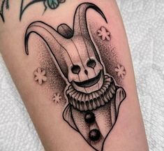 a black and white drawing of a clown mask on the leg with flowers around it