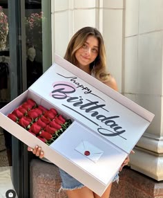 a woman is holding a box with roses in it