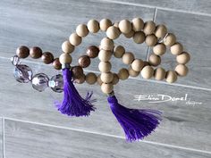 a wooden beaded rosary with purple tassels and beads hanging from it's end