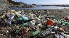 a pile of trash sitting on top of a sandy beach next to the ocean with a basketball ball in it