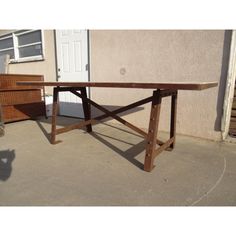 a wooden table sitting on top of a cement floor next to a building with a white door