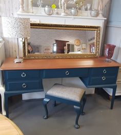 a blue desk with a mirror on top and a stool in front of the table