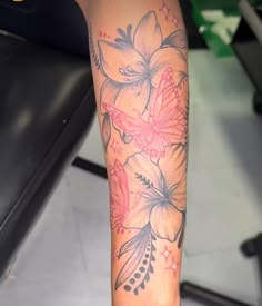 a woman's leg with flowers and butterflies tattooed on her arm, next to a treadmill