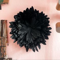 a large black flower mounted to the side of a pink wall next to other items