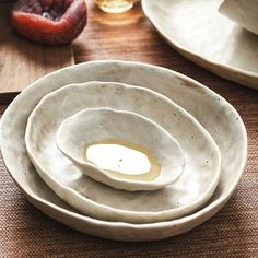 a stack of white plates sitting on top of a wooden table next to other dishes