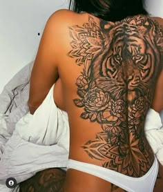 a woman with a tiger tattoo on her back and chest, standing in front of a white wall