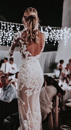 the back of a woman's wedding dress at a dinner table with people in the background