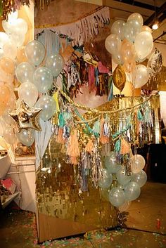 balloons and streamers are hanging from the ceiling in an open room with confetti