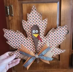 a person is holding up a paper turkey on a doorknob with gingham checkered fabric