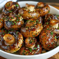 a white bowl filled with mushrooms covered in sesame seeds and garnished with parsley