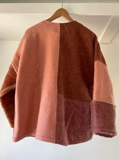 a brown and pink sweater hanging on a wooden hanger