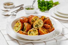 a white bowl filled with potatoes on top of a table