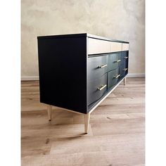 a black and white dresser sitting on top of a hard wood floor