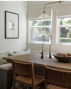 a dining room table with two chairs and a bowl of fruit on the table next to it