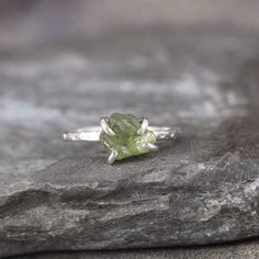 Raw, uncut, rough Peridot is the focus on this handmade sterling silver ring.  The raw, uncut, rough peridot is unique; exactly the way it was created by nature.  This peridot specimen is set in a sterling silver handmade claw setting made specifiaclly for this stone, to reveal the maximum amount of this unique gemstone.  The band on this ring has been textured to compliment the rustic look of the natural raw, uncut, rough peridot.  The peridot measures approximately 6.5mm x 7.5mm.  The width of Raw Cut Engagement Ring, Raw Peridot, Peridot Engagement Rings, August Birthstone Ring, Green Gemstone Ring, Handmade Sterling Silver Rings, Peridot Green, Claw Setting, August Birthstone