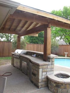 an outdoor bbq and grill area next to a swimming pool