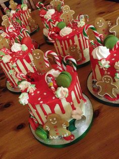 several decorated christmas cakes sitting on top of a wooden table with candy canes and candies