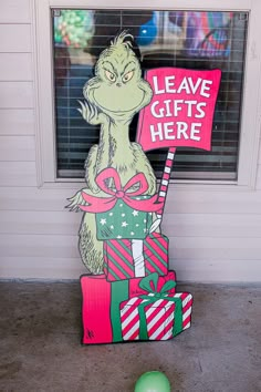 a cardboard cat in the hat holding a sign that says leave gifts here next to a green ball