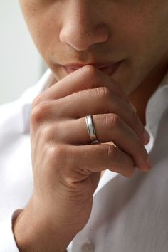 a close up of a person with a ring on their finger and wearing a white shirt