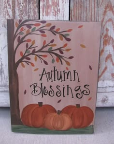 a wooden sign that says autumn blessings with pumpkins in front of a tree