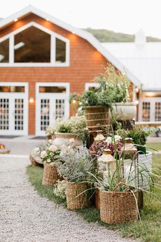 baskets filled with flowers and herbs lined up in front of a barn